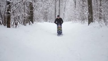 Tuhaf ailenin kış-manzarada sledging genç