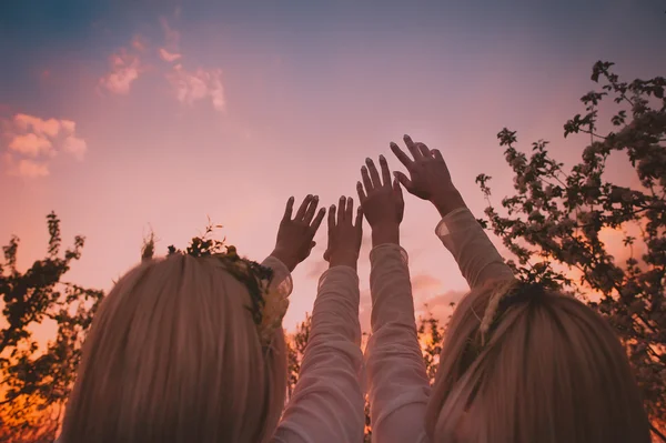 Δίδυμα κορίτσια τεντώνοντας τα χέρια στον ουρανό — Φωτογραφία Αρχείου