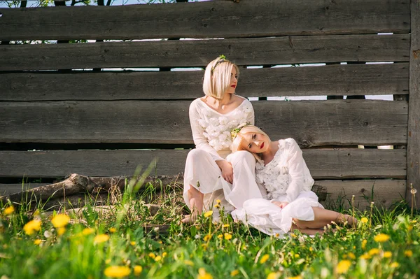 Tvillingsystrar som sitter på en trävägg — Stockfoto