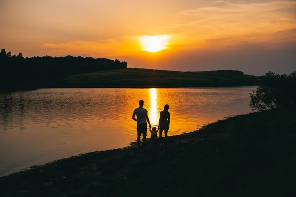 Família feliz juntos ao pôr do sol — Fotografia de Stock