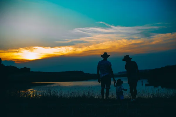 Família feliz juntos ao pôr do sol — Fotografia de Stock