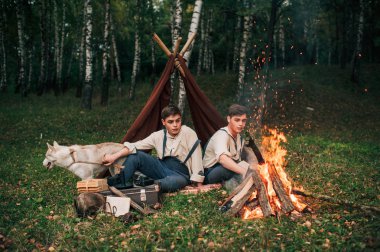 bir kamp ateşi etrafında oturan iki ikiz kardeşler