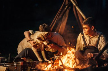 bir kamp ateşi etrafında oturan iki ikiz kardeşler