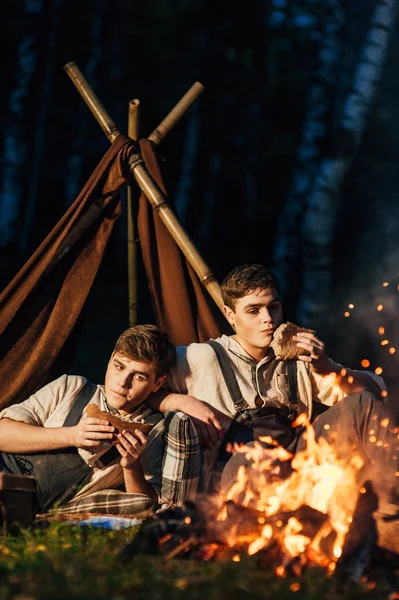 Dois irmãos gêmeos sentados em torno de uma fogueira — Fotografia de Stock