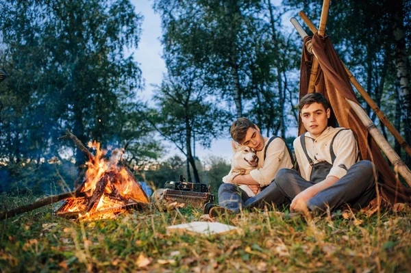 bir kamp ateşi etrafında oturan iki ikiz kardeşler