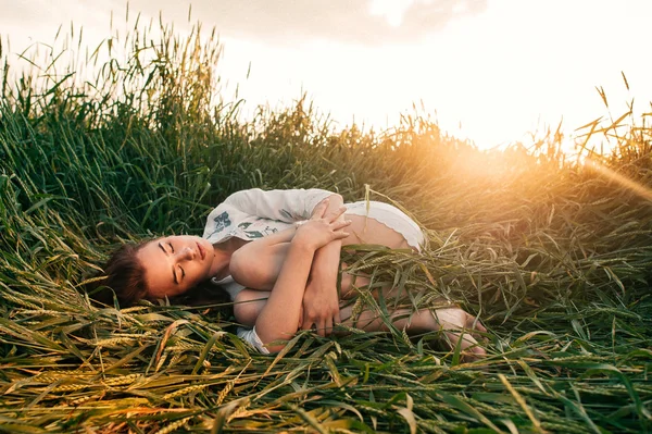 Jovem deitada em um campo de trigo — Fotografia de Stock