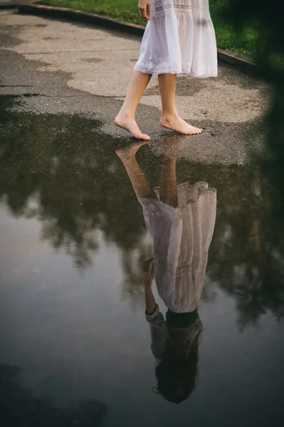 Woman walking barefoot through puddle