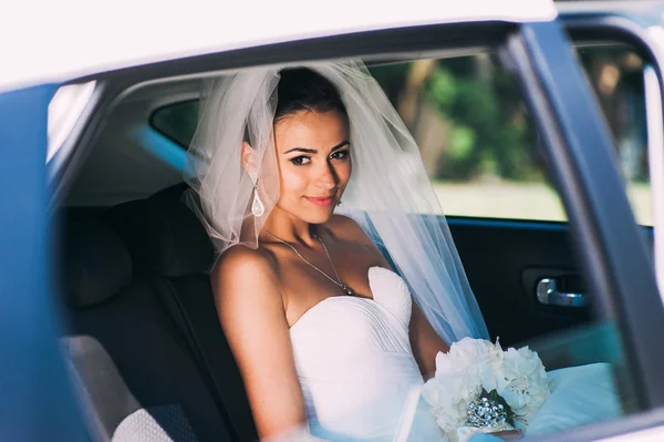 Beauty bride in bridal gown in a car — Stock Photo, Image