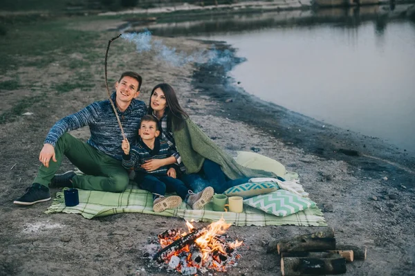 Joyeux jeune famille près du feu de camp — Photo