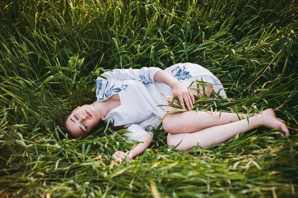 Jovem deitada em um campo de trigo — Fotografia de Stock