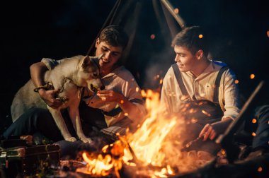 bir kamp ateşi etrafında oturan iki ikiz kardeşler