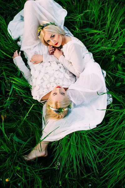 Tweeling zusjes liggen op gras — Stockfoto
