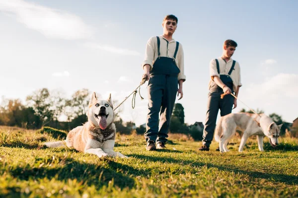 Two twin brothers with husky dogs — Stock Photo, Image
