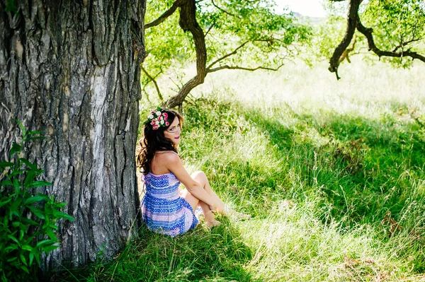 Chica posando en el césped cerca de árbol viejo — Foto de Stock