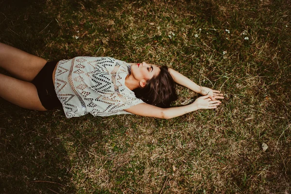 Brunette girl lying on the dry grass — Stock Photo, Image