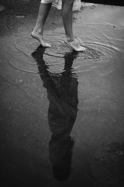 Woman walking barefoot through puddle