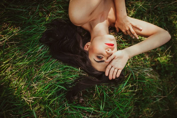 Brünettes Mädchen liegt auf dem trockenen Gras — Stockfoto