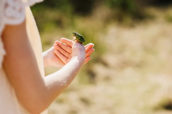 Vrouw bedrijf groene kikker uit handen — Stockfoto