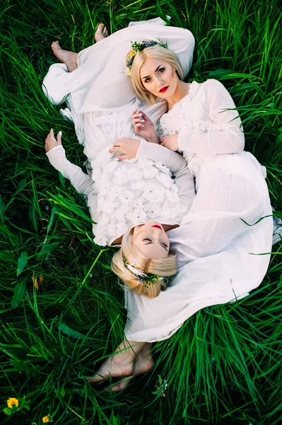 Tvillingar systrar liggande på grönt gräs — Stockfoto