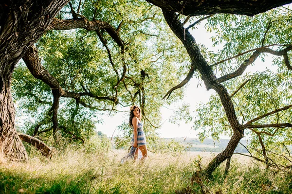 Meisje die zich voordeed op het gazon in de buurt van oude boom — Stockfoto