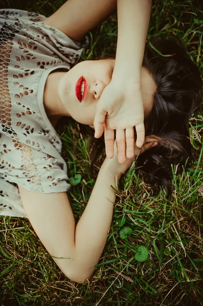Menina morena deitada na grama seca — Fotografia de Stock