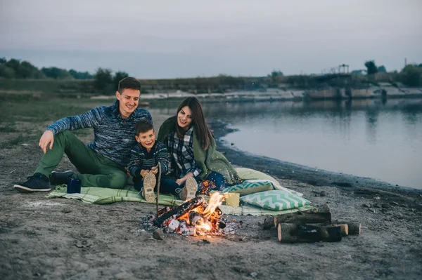 Joyeux jeune famille près du feu de camp — Photo