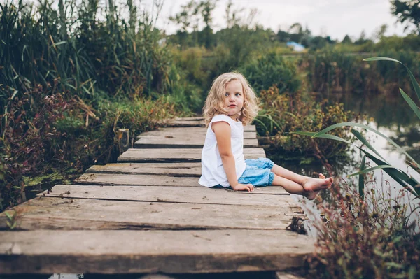 Girl sitting on a wooden pier — Stock Photo, Image