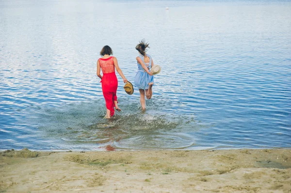 Dos chicas corren hacia el agua —  Fotos de Stock