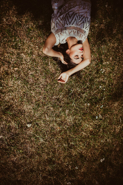 Beautiful girl lying in the dry grass with place for text