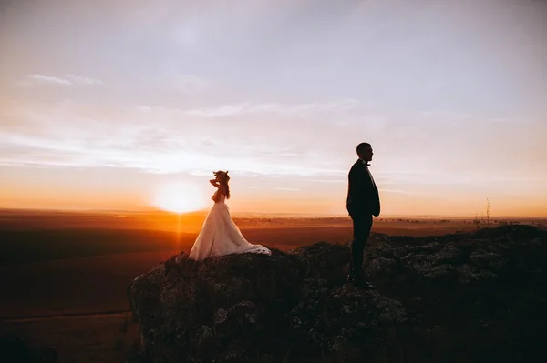 Mariée et marié sur fond de coucher de soleil — Photo