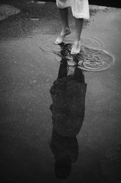 Woman walking barefoot through puddle  