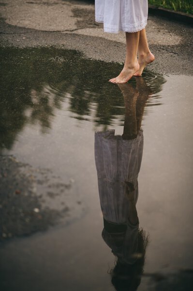 Woman walking barefoot through puddle  