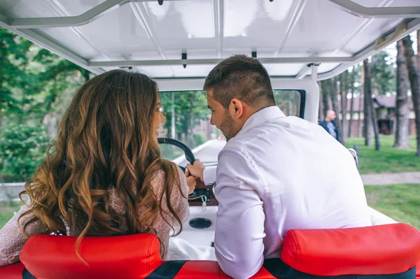 Novia y novio conduciendo un carrito de golf — Foto de Stock