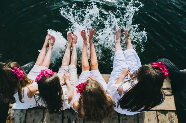 Piger venner sidder ved vandet - Stock-foto