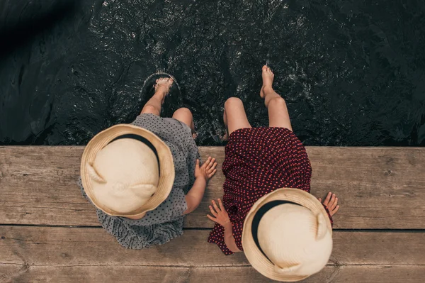Молоді дівчата занурюються ногами в озеро — стокове фото