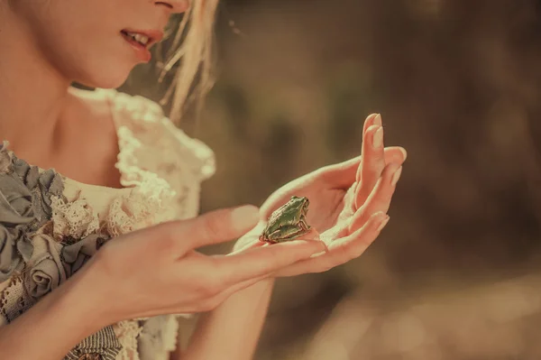 Девушка держит зеленую лягушку — стоковое фото
