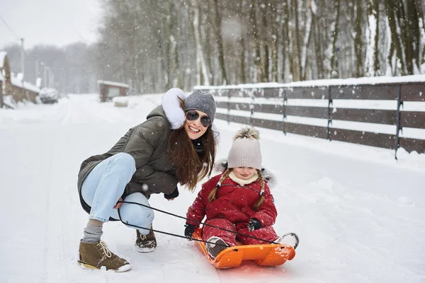 A young beautiful mom sledges her baby — Stock Photo, Image