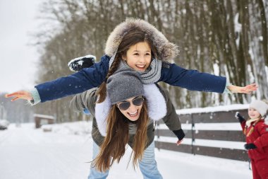 Genç bir anne ve ağaç çocukları eğleniyor ve evin yakınında dışarıda oynuyorlar.