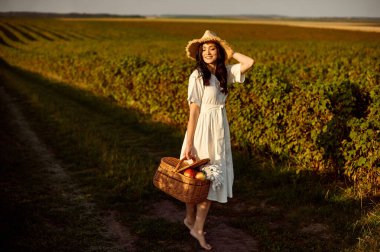 Hasır şapkalı ve frenk üzümü tarlasında sepeti olan bir kız..