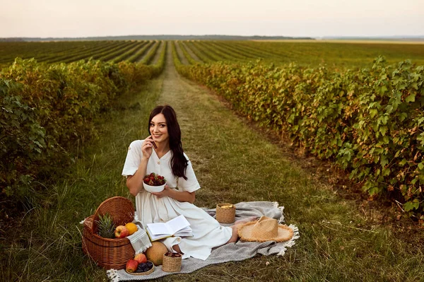 Dziewczyna siedzi na kratę na polu w pobliżu owoców. — Zdjęcie stockowe