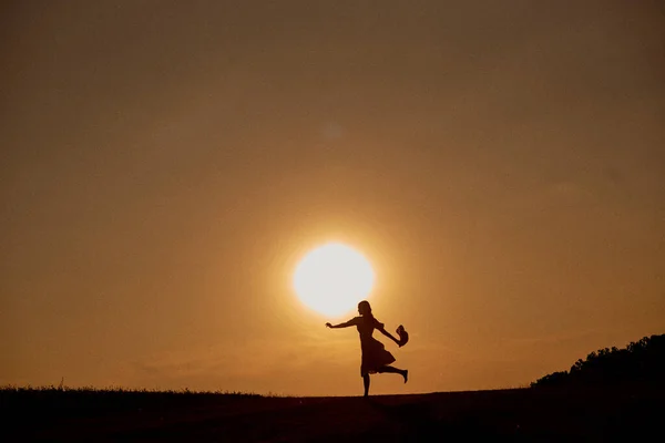 Silhouette d'une fille courant à travers le champ. — Photo