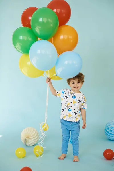 Mavi arka planda balonlarla poz veren neşeli çocuk portresi — Stok fotoğraf