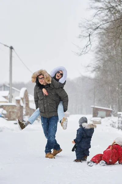 Glückliche Familie vergnügt sich im Winter draußen vor dem Haus — Stockfoto