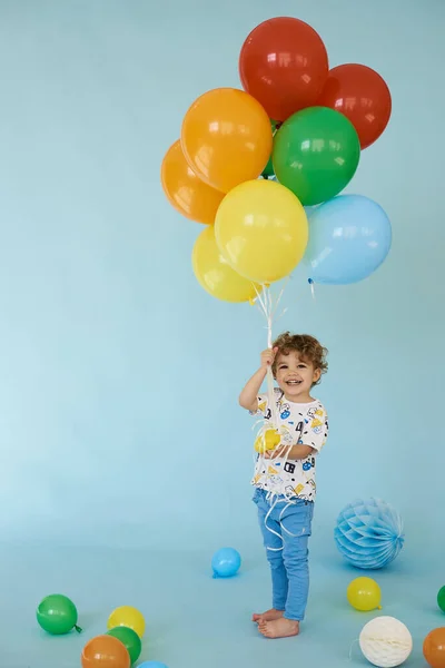 Mavi arka planda balonlarla poz veren neşeli çocuk portresi — Stok fotoğraf
