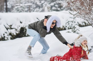 Genç bir anne ve çocukları eğleniyor ve evin yakınında dışarıda oynuyorlar.