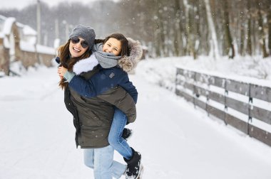 Genç bir anne ve çocukları eğleniyor ve evin yakınında dışarıda oynuyorlar.