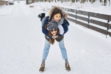 Genç bir anne ve ağaç çocukları eğleniyor ve evin yakınında dışarıda oynuyorlar.