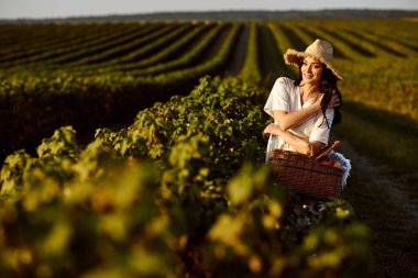 Hasır şapkalı ve frenk üzümü tarlasında sepeti olan bir kız..