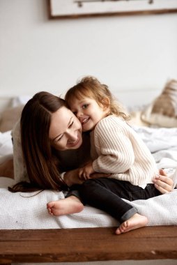 Anne ve küçük kızı Noel dekoru olan parlak bir yatak odasında eğleniyor ve oyun oynuyorlar..