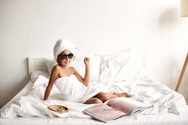 선글라스를 매력적 둘레에 수건이 침대에 잡지를 스러운 방식의 어린이 — 스톡 사진